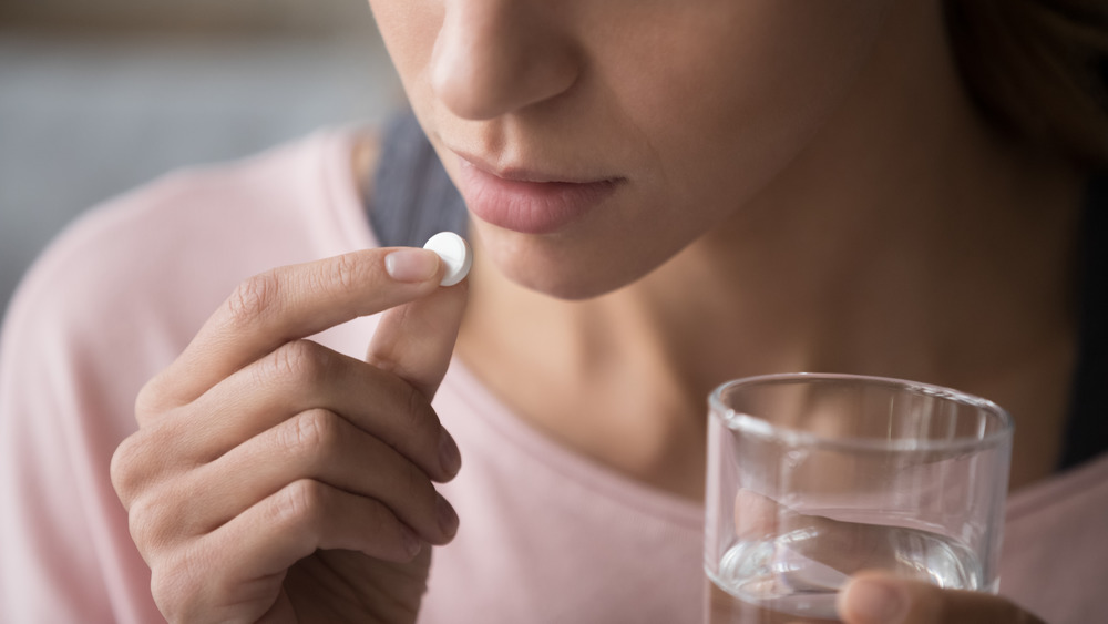 Close up of woman taking aspirin with water